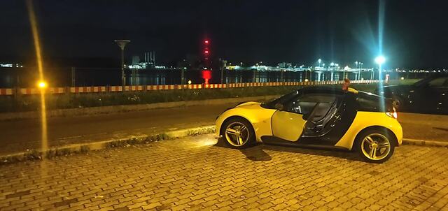 Nachtaufnahme des Roadsters vor der beleuchteten Uferpromenade